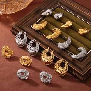 Chic gold and silver oval hoop earrings displayed on green velvet in a wood jewelry box