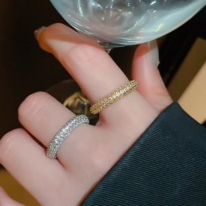 Close-up of gold and silver twisted open rings with zircons on a model holding a glass