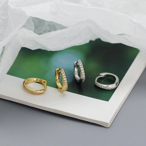 Close-up of small irregular S925 silver hoop earrings with zircon inlay in gold and silver