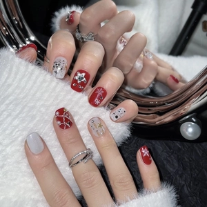 Faux ongles de Noël rouges et blancs avec motifs flocons de neige, perles et strass brillants