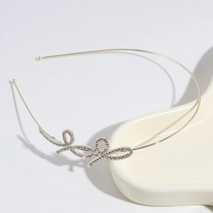 Elegant gold headband with rhinestone bow design placed on a ceramic tray