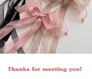 Detail of pink satin bow with organza ribbons and pearl pendants for hair accessories