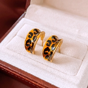 Detail of vintage leopard print C-shape hoop earrings with gold trim on suede display