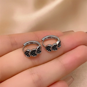 Close-up of silver earrings with three connected hearts micro-set with black zircon stones