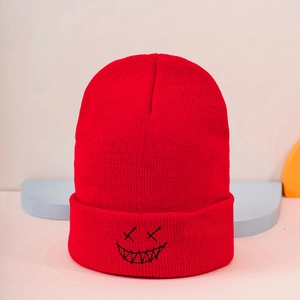 Detail of red knitted beanie featuring black embroidered quirky ghost face pattern