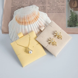 Golden pearl necklace and floral earrings set on elegant jewelry display cards