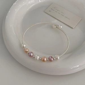 Detail of multi-color freshwater pearl bracelet on white porcelain with silver accents