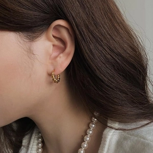 Macro detail of gold twist hoop earring featuring a minimalist spiral design for women