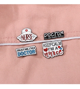 Détail de quatre broches médicales en émail avec slogans pour infirmières sur tissu rose