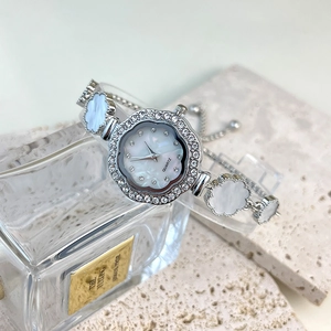 Macro detail of luxury floral quartz watch with clover bracelet and shimmering crystals