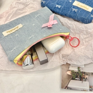 Detail of denim coin pouch showing pink ribbon bows and easy-pull ring zipper