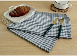 Close-up of grey and white checkered linen napkin on a wooden table with cutlery