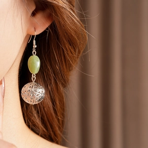 Close-up of vintage resin hollow pendant earrings on model with green oval beads