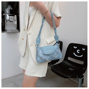Close-up of light blue leather bag with flower pendant chain and woven strap detail