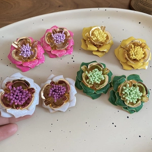 Gros plan détaillé de boucles d'oreilles fleurs en émail rose, jaune et vert