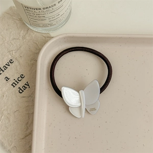 Detailed macro view of an elegant white acetate bow hair tie with glossy texture