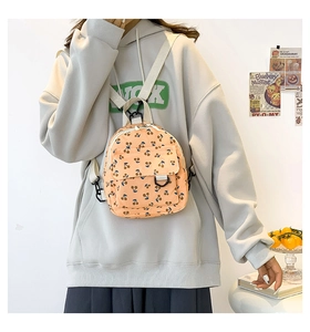 Detailed view of yellow corduroy mini backpack featuring cherry prints on a female model