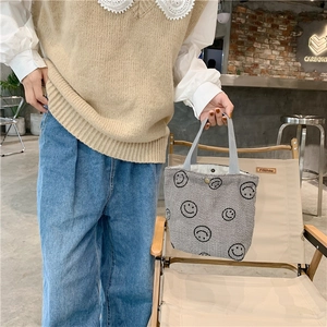 Detail of grey corduroy tote bag with embroidered smileys and snap button closure