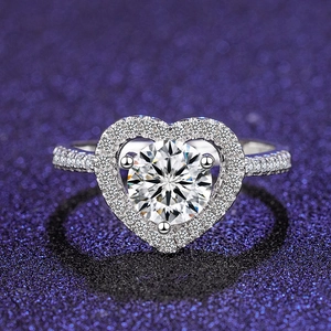 Macro shot of silver heart-shaped ring featuring a brilliant center stone and pavé setting