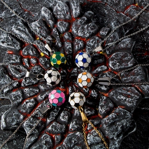 Detailed close-up of colorful enamel soccer ball pendants on textured volcanic rock background