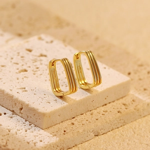 Macro shot of minimalist gold S925 sterling silver geometric rectangular earrings on stone