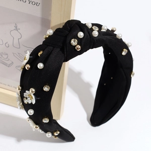 Elegant black twist headband with white flowers, pearls, and crystals on a display