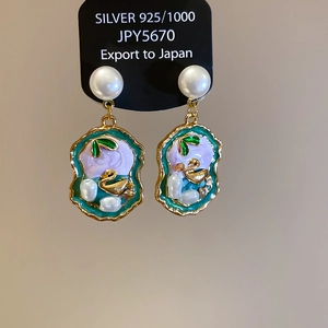 Detail of 925 silver earrings with purple enamel, pearls and golden leaves on display