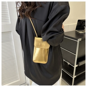 Chic gold rectangular crossbody phone bag with slim shoulder strap worn by a female model