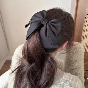 Elegant large black satin bow banana clip on long wavy hair for a stylish ponytail
