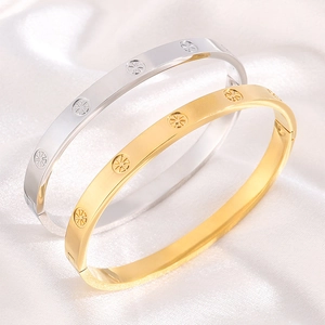 Detail of gold and silver flat bracelets with radial star patterns on white silk background