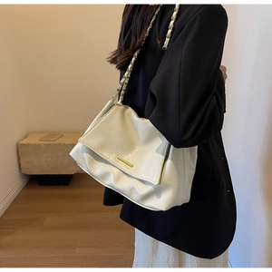 Detail of elegant cream large capacity shoulder bag with chain strap and gold hardware