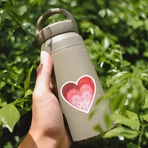 Waterproof heart stickers applied to a beige thermal water bottle with outdoor water droplets