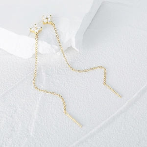Detail of gold flower earrings with micro-pave zircons and delicate long link chains