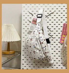 Detail of white waist bag with cartoon dog prints and adjustable strap on pegboard