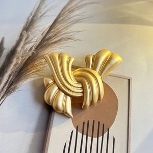 Gros plan d'une broche noeud dorée mate de style vintage avec texture rayée