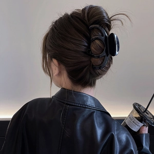 Large black minimalist hair claw clip shown on a woman's bun hairstyle in daily life