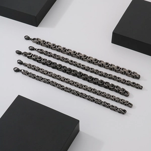 Five dark grey stainless steel Byzantine chain bracelets with lobster clasps on a white background