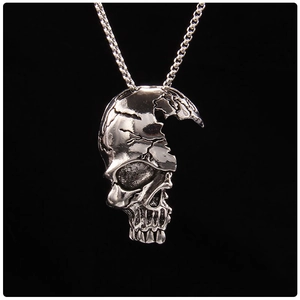 Détail du collier tête de mort punk argenté avec texture fissurée et finition vintage