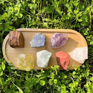 Natürliches Rohkristall-Set mit 7 Chakra-Steinen in Bambusschale auf grünem Rasen