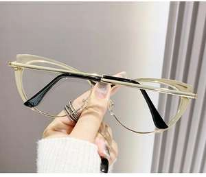 Detail of gold cat-eye glasses with metal frames and black tips held by hand