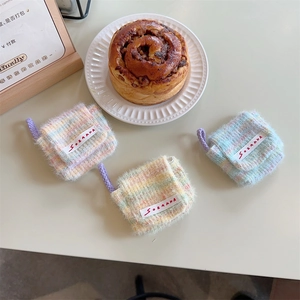 Dettaglio di mini custodie per auricolari in peluche dai colori pastello sul tavolo