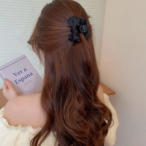 Elegante pinza per capelli con fiocco nero in nastro su lunghi capelli castani mossi