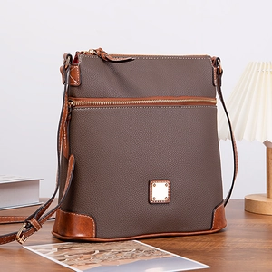 Detailed view of brown pebble grain leather crossbody bag with golden hardware and red lining