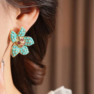 Macro view of vintage floral stud earrings with turquoise petals and ruby centers