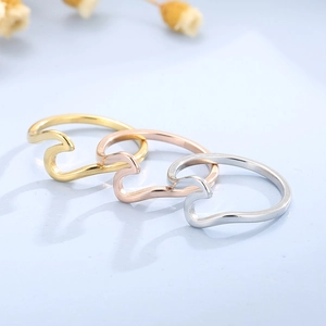 Detailed close-up of wave-shaped rings in gold, rose gold, and silver stainless steel