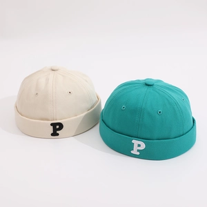 Detail of cream and teal cotton docker hats for kids with embroidered P letter design