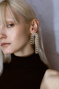 Detail of elegant gold fringe earrings with multiple rows of sparkling diamonds on model
