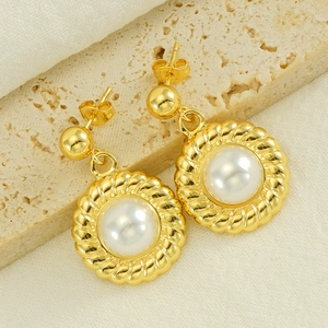 Elegant gold stainless steel sunflower pearl earrings displayed on a natural stone base