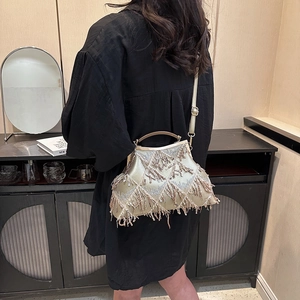 Golden sequin shell bag with fringe detail shown on shoulder with long strap