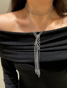 Detail showing elegant long fringe silver beaded necklace on a model with sleek black outfit